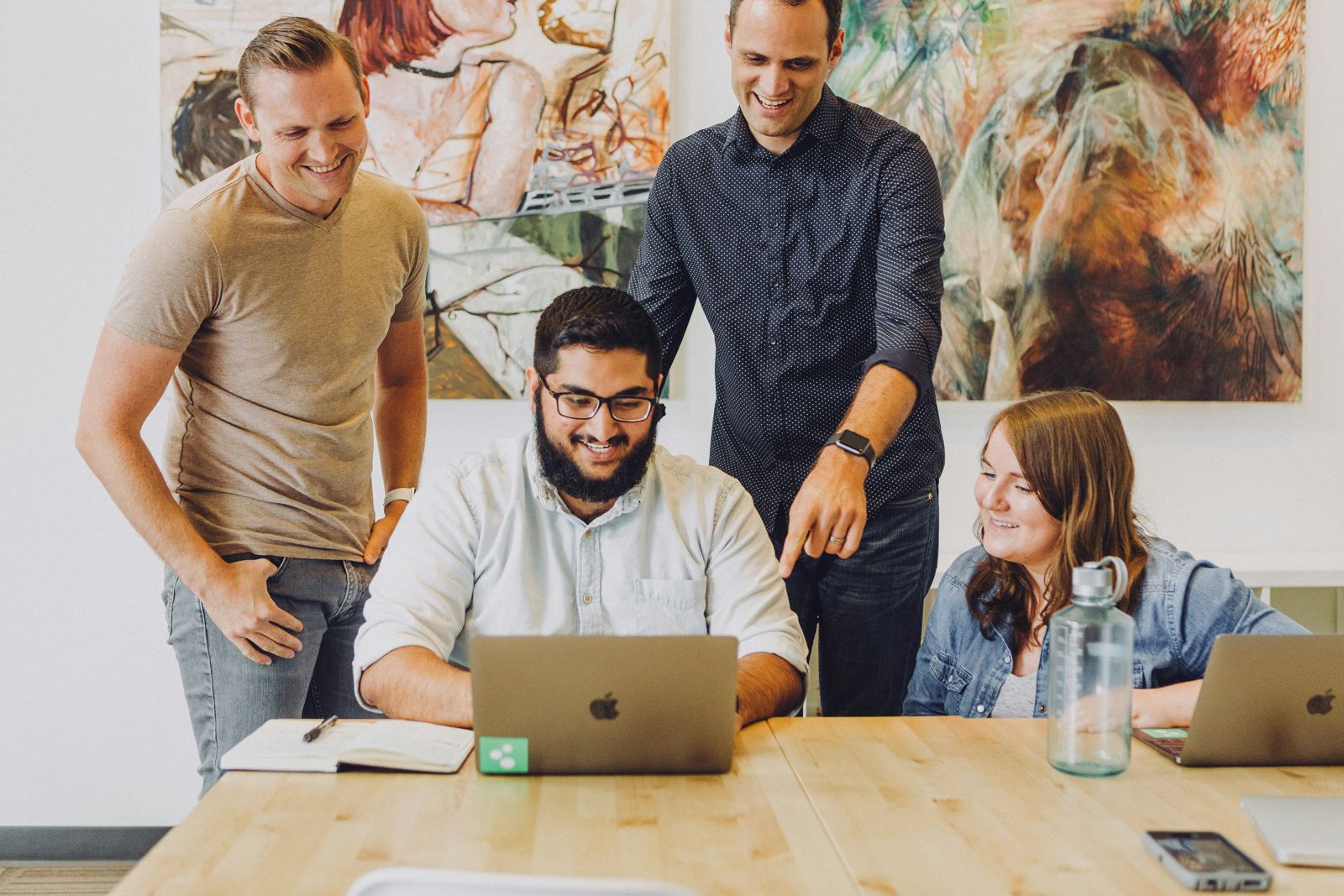 Colleagues smiling together while working on a laptop