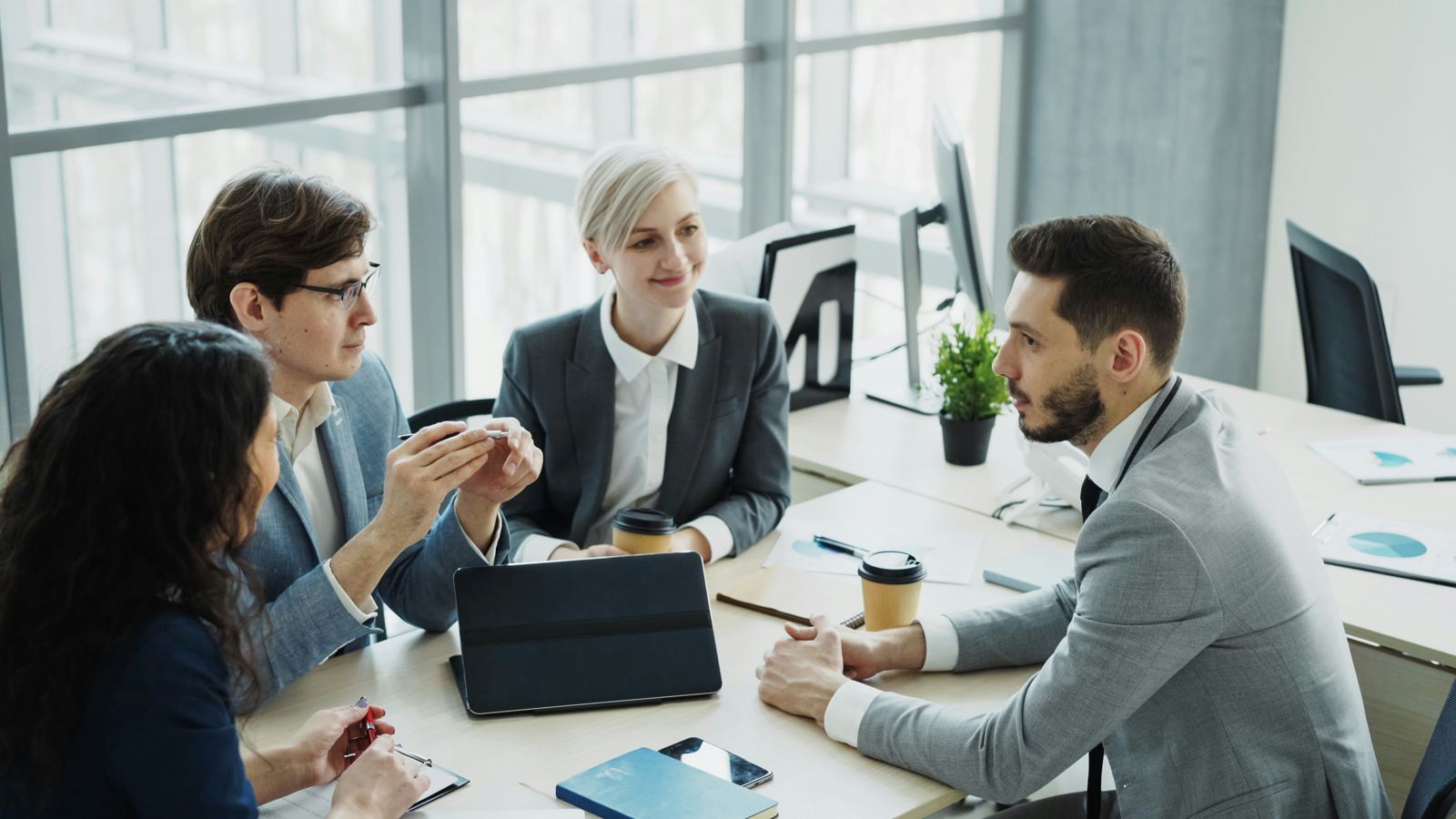 A team of four professionals collaborating around a table in a bright office